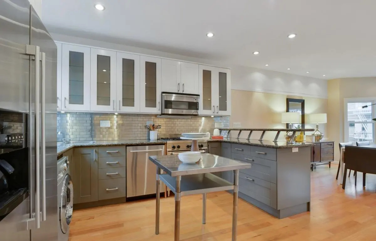 Open kitchen renovation with modern lighting, glass cabinetry, and a functional island in San Francisco’s Lower Haight neighborhood.