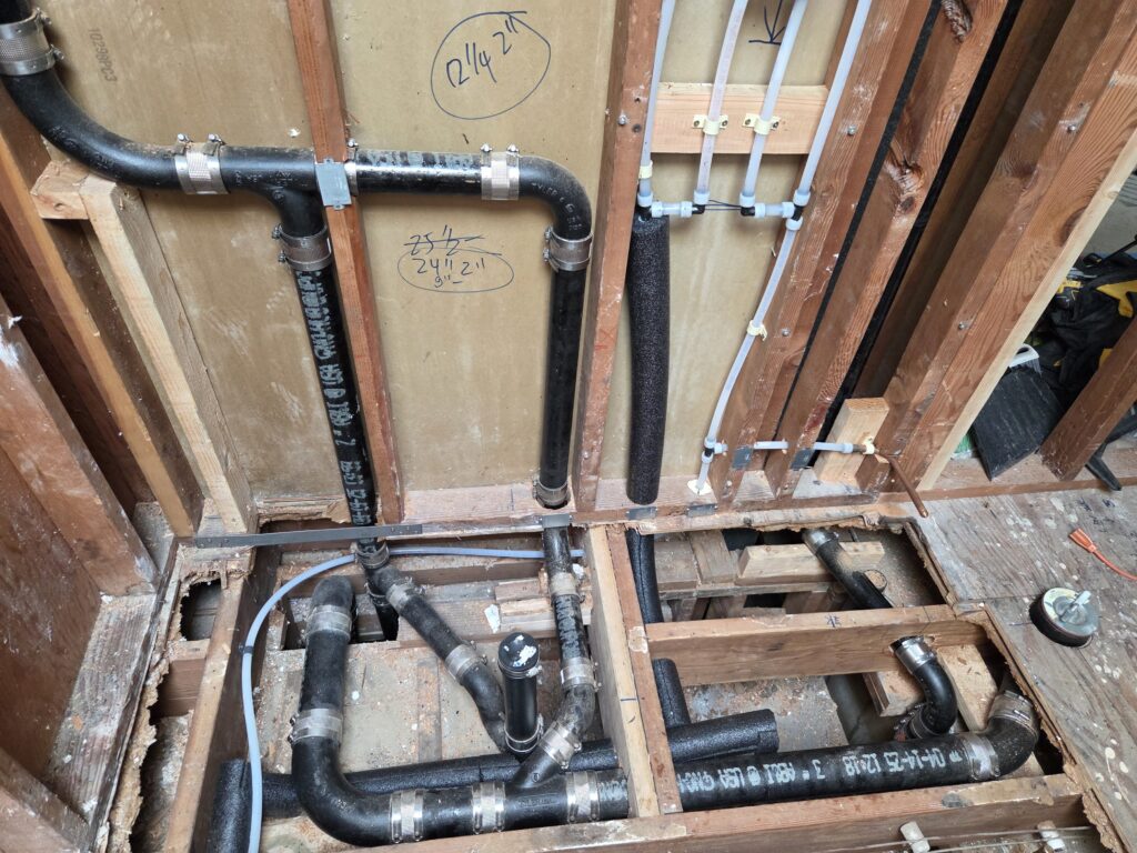 Bathroom rough-in with cast iron DWV and PEX supply for toilet and shower in San Francisco home renovation.