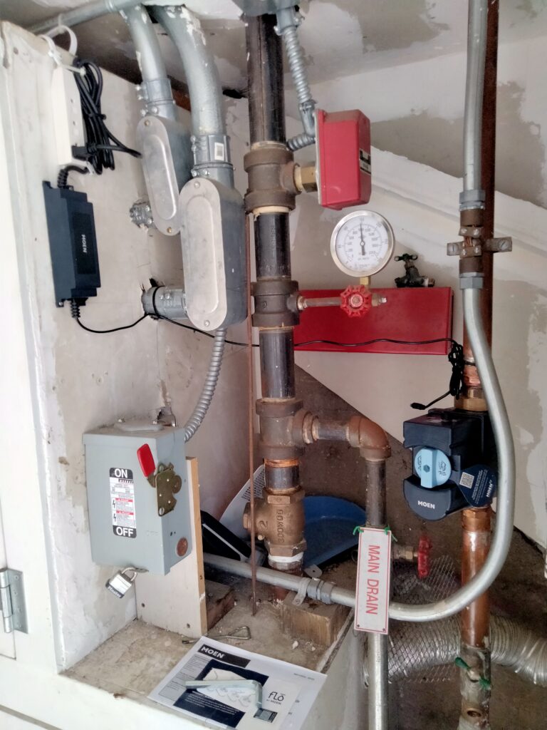 1-inch Moen Flo leak detection and shutoff device installed on copper piping in tight San Francisco utility room.