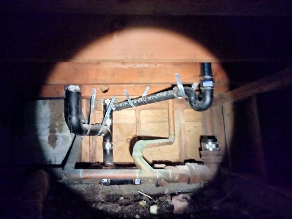 San Francisco crawl space plumbing showing cast-iron and ABS wet-vent rough-in for ADU toilet and shower, installed in a tight, low-clearance area.